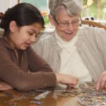 Child and senior citizen completing a puzzle
